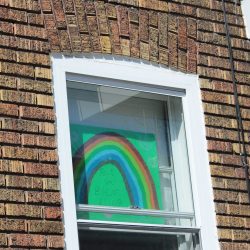 Dans une fenêtre, un arc-en-ciel et l'inscription "Ça va bien aller"